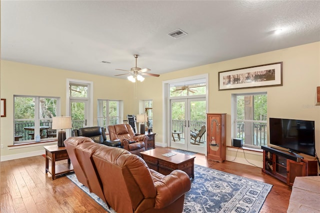 living room featuring wood-type flooring, a ceiling fan, and a healthy amount of sunlight