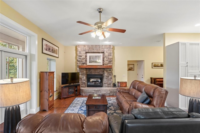 living area with ceiling fan, a fireplace, and wood finished floors