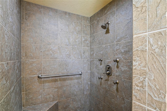 bathroom with a textured ceiling and a tile shower