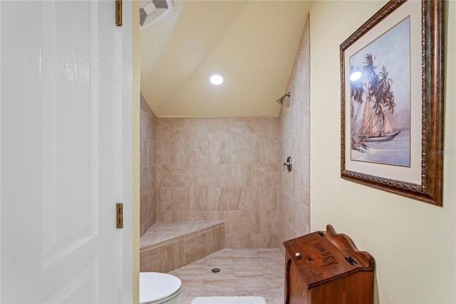 bathroom featuring toilet, vaulted ceiling, and tiled shower