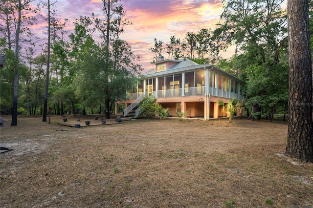 rear view of house with metal roof, stairs, a sunroom, and a patio area