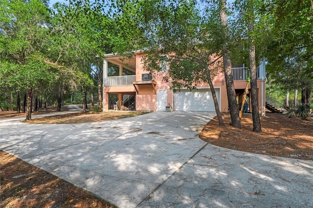 view of front of house featuring stucco siding, driveway, stairs, and a garage