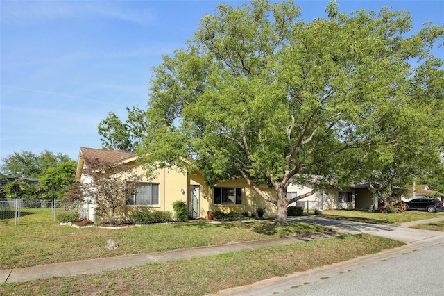 12906 Sandburst Ln, Hudson, FL 34667 - view of property hidden behind natural elements with concrete driveway, fence, a front yard, and stucco siding