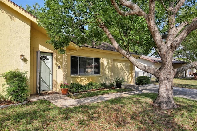 12906 Sandburst Ln, Hudson, FL 34667 - view of front of house featuring a garage, a front lawn, and stucco siding