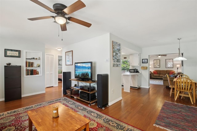 12906 Sandburst Ln, Hudson, FL 34667 - living room with dark wood-type flooring, a ceiling fan, baseboards, and built in features