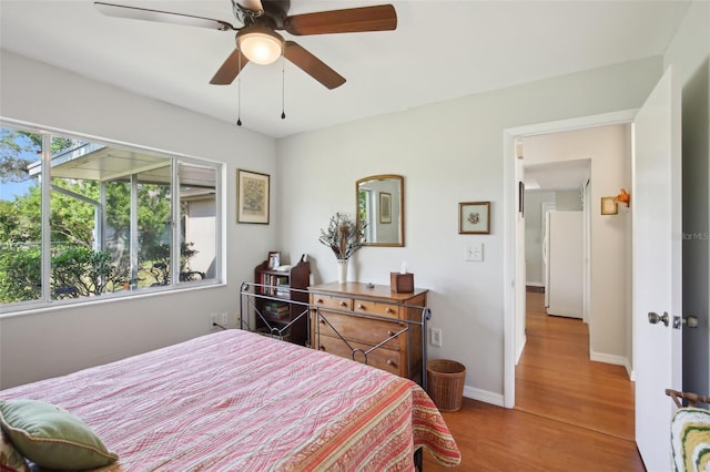 12906 Sandburst Ln, Hudson, FL 34667 - bedroom with freestanding refrigerator, a ceiling fan, baseboards, and wood finished floors