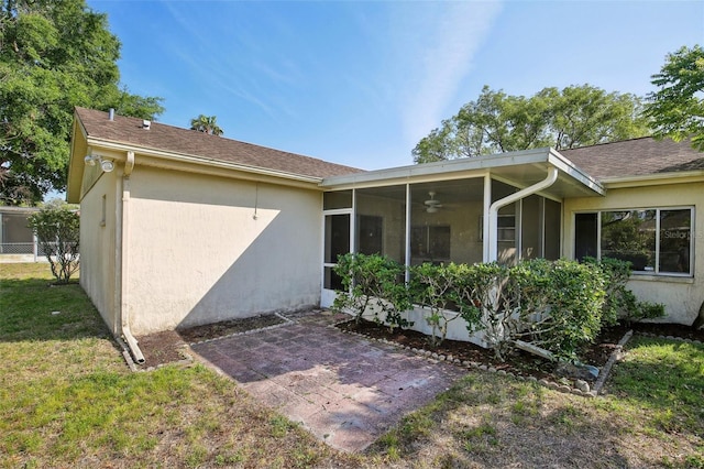 12906 Sandburst Ln, Hudson, FL 34667 - back of house with a ceiling fan, stucco siding, a sunroom, and a patio area
