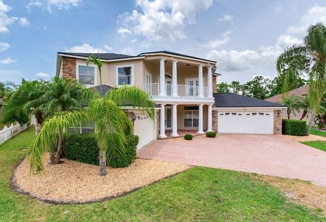 15906 Prince William Pl, Odessa, FL 33556 - neoclassical / greek revival house featuring a balcony, decorative driveway, stone siding, stucco siding, and a garage