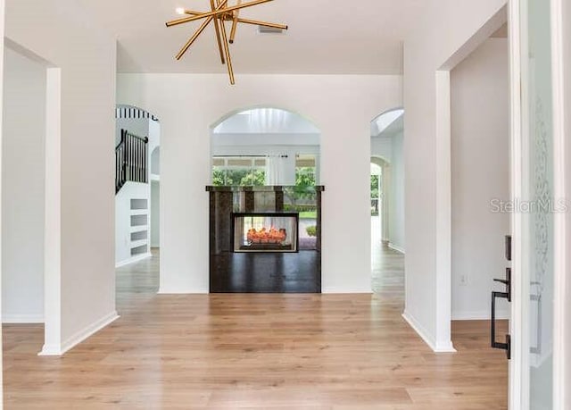 15906 Prince William Pl, Odessa, FL 33556 - foyer entrance featuring light wood-style flooring, a multi sided fireplace, arched walkways, and baseboards