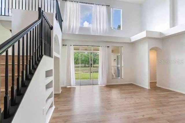 15906 Prince William Pl, Odessa, FL 33556 - unfurnished living room featuring a high ceiling, arched walkways, wood finished floors, baseboards, and stairs