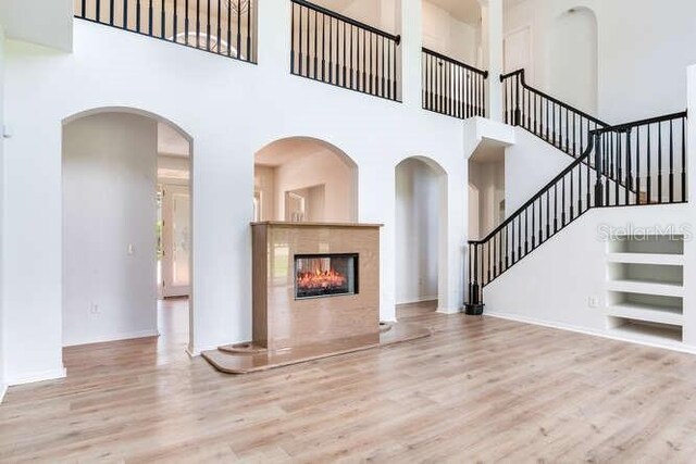 15906 Prince William Pl, Odessa, FL 33556 - unfurnished living room with wood finished floors, built in features, a high ceiling, stairway, and a tile fireplace