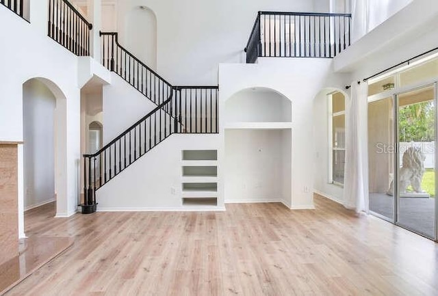 15906 Prince William Pl, Odessa, FL 33556 - unfurnished living room with a high ceiling, stairway, wood finished floors, arched walkways, and baseboards