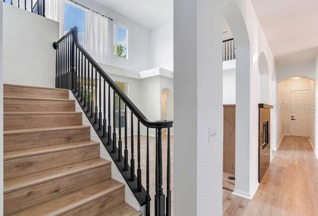 15906 Prince William Pl, Odessa, FL 33556 - stairs featuring arched walkways, wood finished floors, baseboards, and a high ceiling