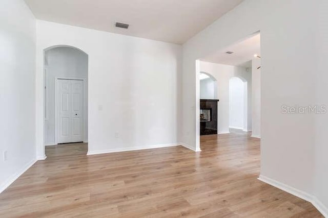 15906 Prince William Pl, Odessa, FL 33556 - spare room with arched walkways, a fireplace, light wood finished floors, and baseboards
