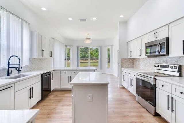 15906 Prince William Pl, Odessa, FL 33556 - kitchen with stainless steel appliances, a sink, a kitchen island, tasteful backsplash, and recessed lighting