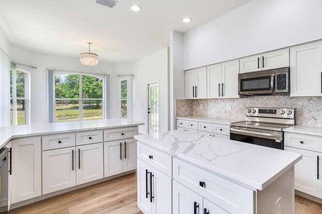 15906 Prince William Pl, Odessa, FL 33556 - kitchen with appliances with stainless steel finishes, backsplash, light wood-style flooring, light stone counters, and white cabinetry