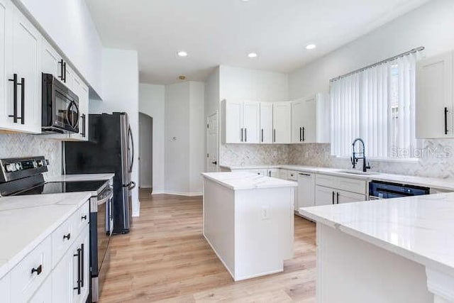 15906 Prince William Pl, Odessa, FL 33556 - kitchen featuring black appliances, a sink, light stone countertops, decorative backsplash, and light wood-type flooring