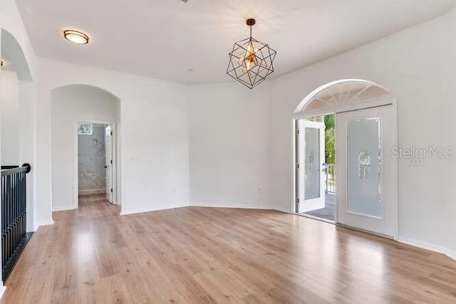 15906 Prince William Pl, Odessa, FL 33556 - empty room with arched walkways, light wood-type flooring, baseboards, and a chandelier