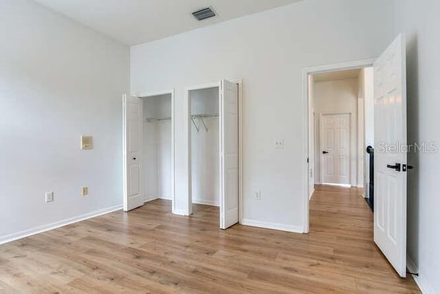 15906 Prince William Pl, Odessa, FL 33556 - unfurnished bedroom with two closets, light wood finished floors, and baseboards