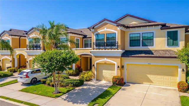 view of front of home with a garage, stucco siding, driveway, and a balcony