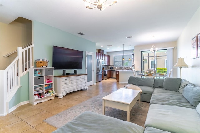 living room with a chandelier, light tile patterned flooring, and baseboards