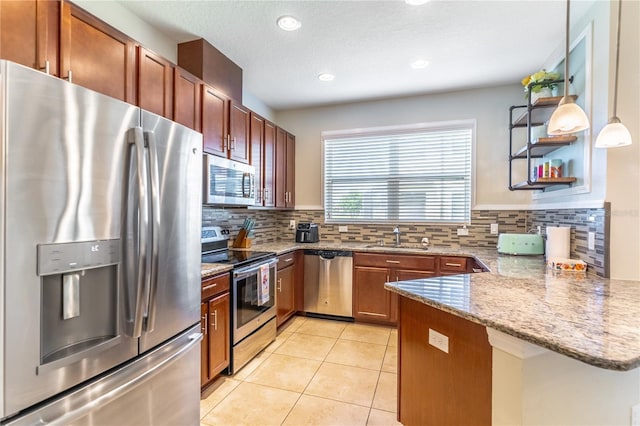 kitchen with appliances with stainless steel finishes, a sink, a peninsula, backsplash, and light tile patterned flooring