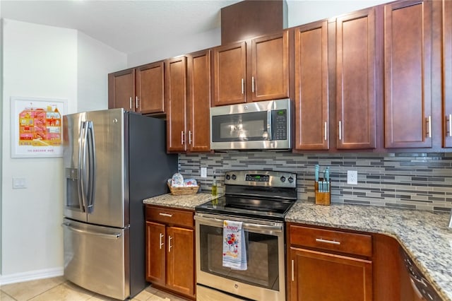 kitchen featuring stainless steel appliances, tasteful backsplash, light stone counters, light tile patterned floors, and baseboards