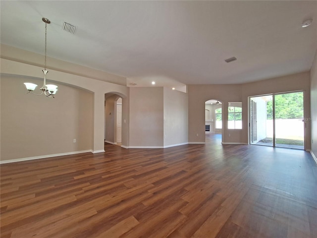 19855 Ellendale Dr, Land O Lakes, FL 34638 - unfurnished living room with arched walkways, a chandelier, dark wood-type flooring, baseboards, and recessed lighting