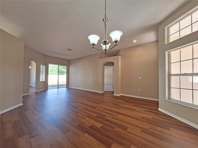 19855 Ellendale Dr, Land O Lakes, FL 34638 - empty room featuring arched walkways, dark wood finished floors, a chandelier, baseboards, and recessed lighting