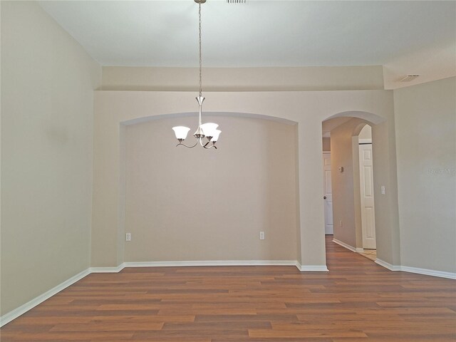 19855 Ellendale Dr, Land O Lakes, FL 34638 - spare room with wood finished floors, a chandelier, arched walkways, and baseboards
