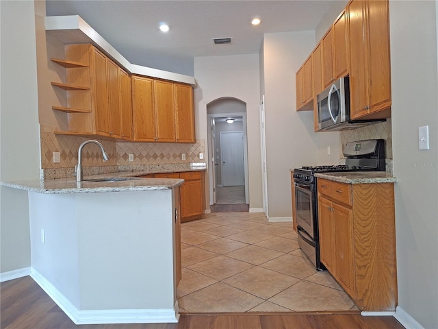 19855 Ellendale Dr, Land O Lakes, FL 34638 - kitchen featuring appliances with stainless steel finishes, a sink, open shelves, a peninsula, and light stone countertops