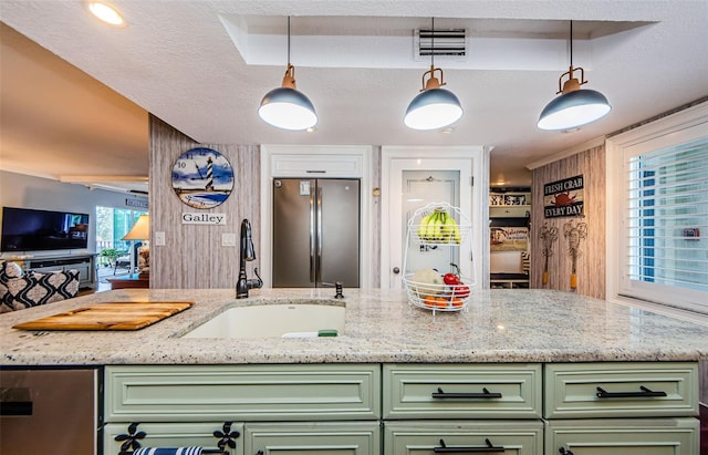 8210 Aquila St Unit 218, Port Richey, FL 34668 - kitchen featuring green cabinetry, appliances with stainless steel finishes, a sink, light stone counters, and decorative light fixtures