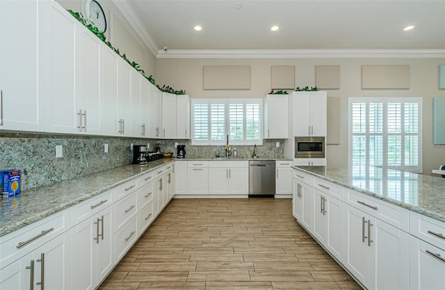 8210 Aquila St Unit 218, Port Richey, FL 34668 - kitchen with stainless steel appliances, ornamental molding, tasteful backsplash, light wood-style flooring, and white cabinets