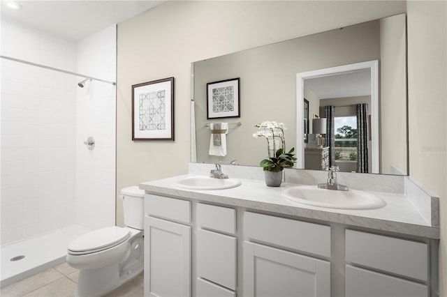 bathroom featuring double vanity, a sink, a tile shower, and toilet
