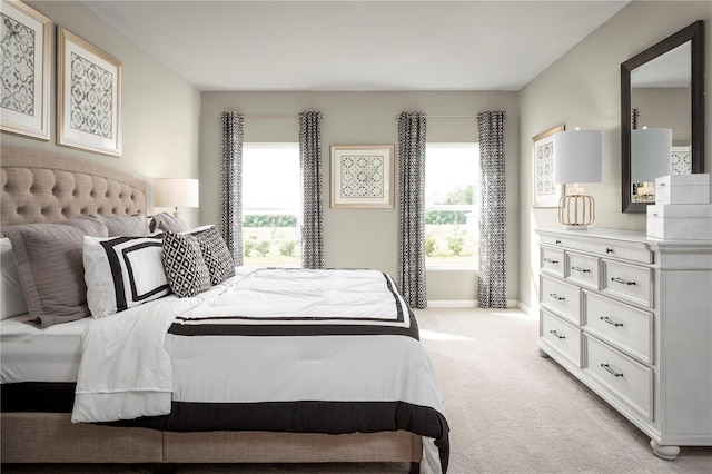 bedroom featuring light colored carpet, baseboards, and multiple windows