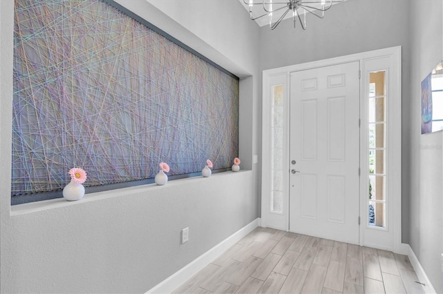 entrance foyer with baseboards, wood finish floors, and a notable chandelier