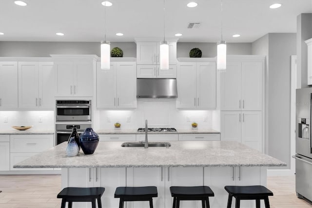 kitchen featuring visible vents, a kitchen breakfast bar, white cabinetry, under cabinet range hood, and appliances with stainless steel finishes