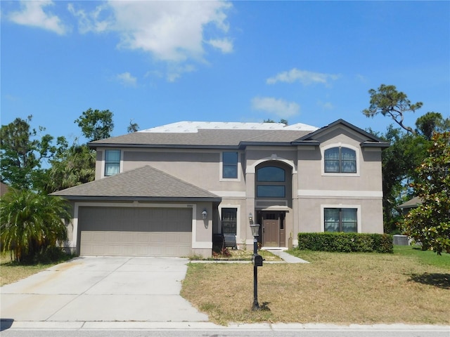 traditional home featuring a front lawn, stucco siding, a shingled roof, an attached garage, and driveway