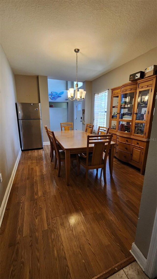 9007 49th Ave E, Palmetto, FL 34221 - dining space featuring a chandelier, dark wood-type flooring, a textured ceiling, and baseboards