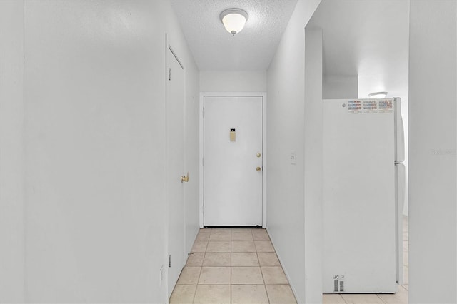 hallway featuring a textured ceiling and light tile patterned floors