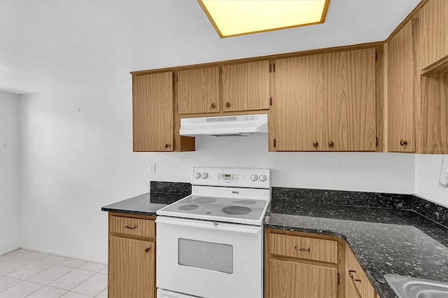 kitchen featuring dark stone counters, electric range, under cabinet range hood, and light tile patterned flooring