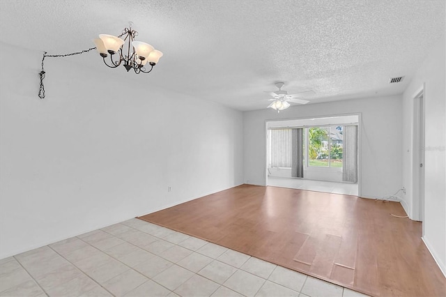 spare room featuring ceiling fan with notable chandelier, light wood finished floors, a textured ceiling, and visible vents