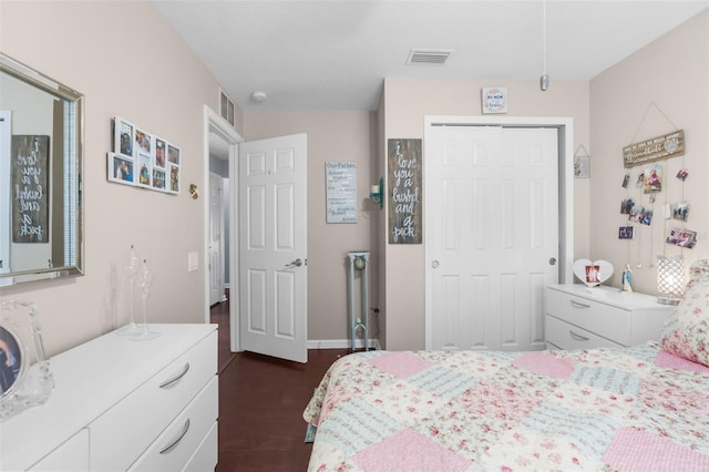 bedroom featuring baseboards, dark wood finished floors, visible vents, and a closet