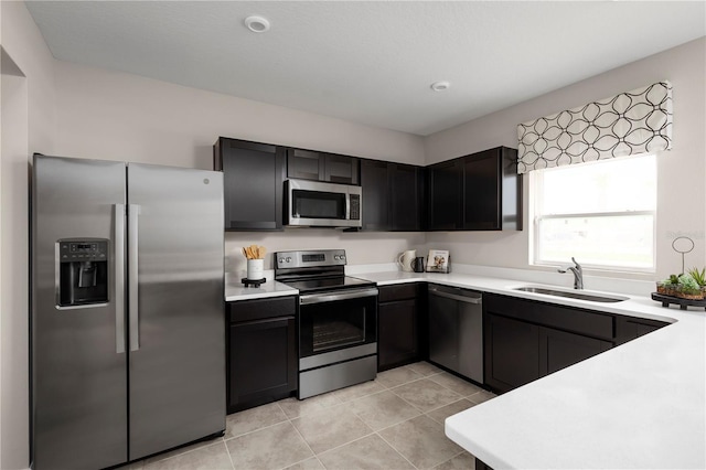kitchen featuring light countertops, stainless steel appliances, light tile patterned flooring, and a sink