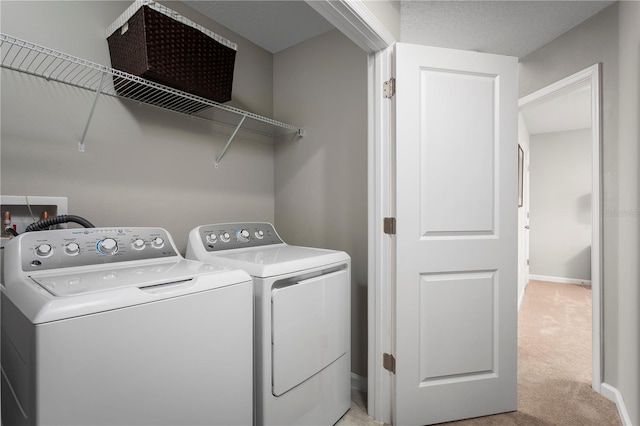 washroom featuring washer and dryer, laundry area, light colored carpet, and baseboards