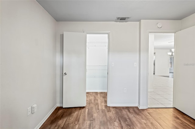 unfurnished bedroom featuring a spacious closet, wood finished floors, and visible vents