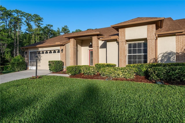 prairie-style home featuring brick siding, an attached garage, driveway, and a front lawn