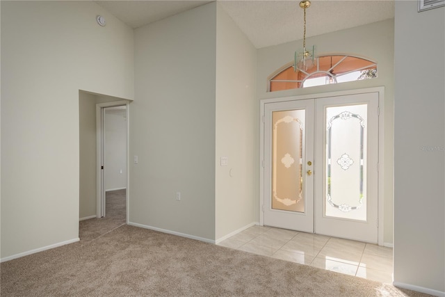 foyer with baseboards, a notable chandelier, french doors, and carpet