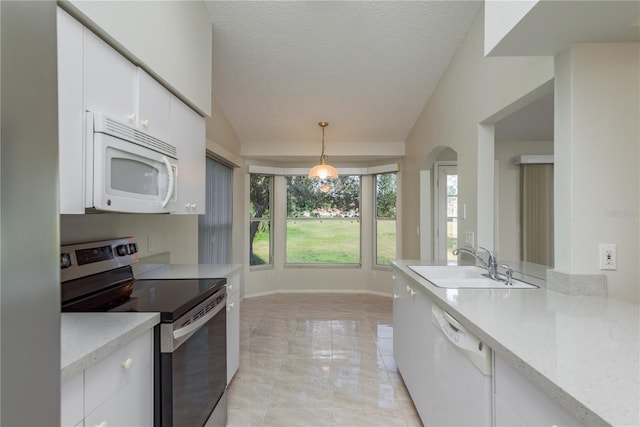 kitchen with a sink, vaulted ceiling, white appliances, and white cabinetry