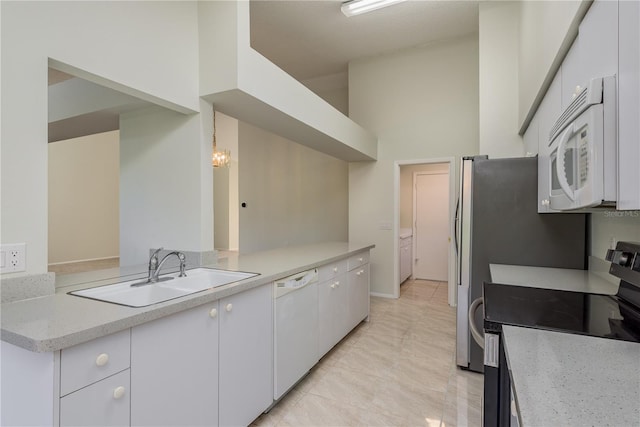 kitchen with a sink, white cabinets, white appliances, and light stone countertops